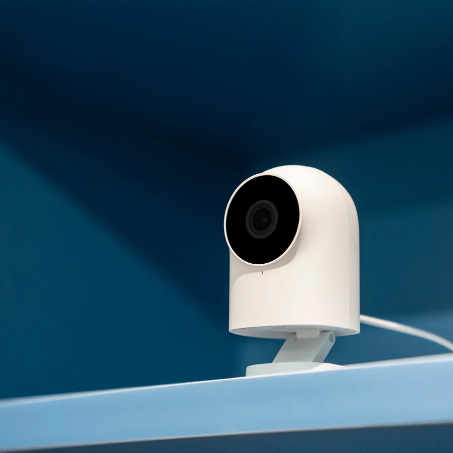 White security camera on a blue shelf.