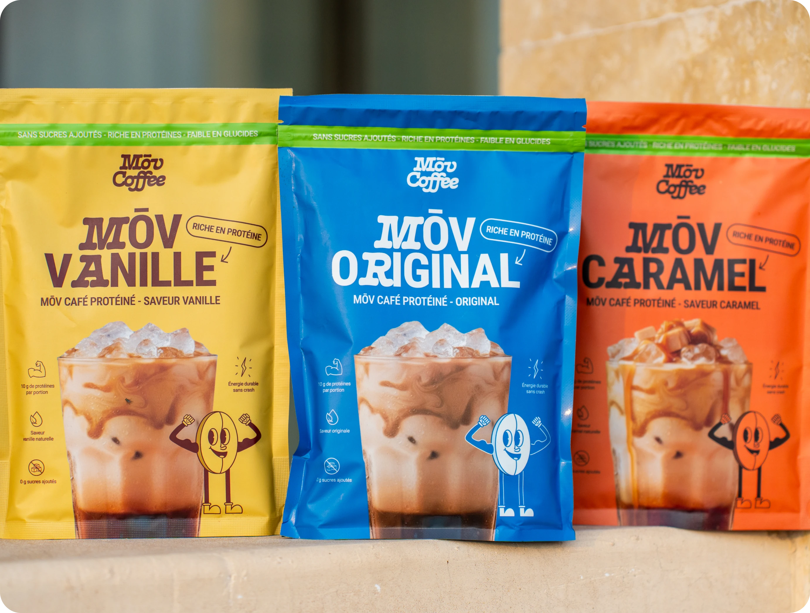 Three colorful pouches of Mōv Coffee protein mix in vanilla, original, and caramel flavors.
