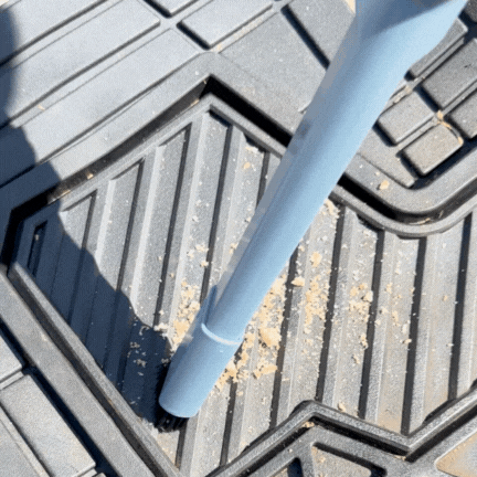 A vacuum cleaner nozzle cleaning crumbs from a car floor mat.