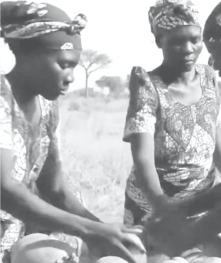 Three women in patterned dresses working together outdoors.