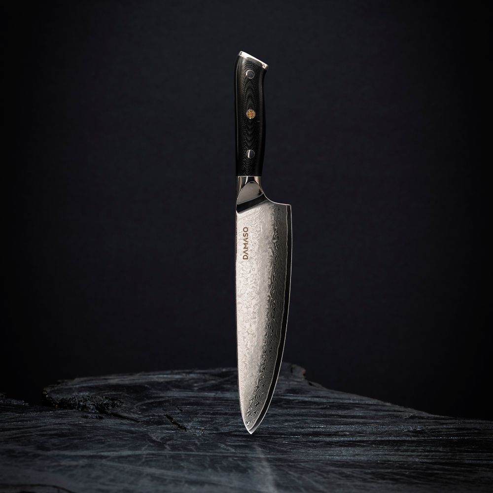 A silver chef's knife with a black handle on a dark background.