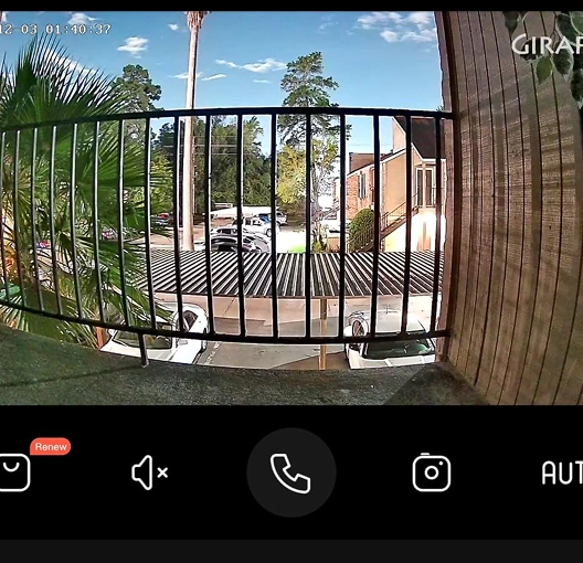 View from a balcony with trees and parked cars visible.