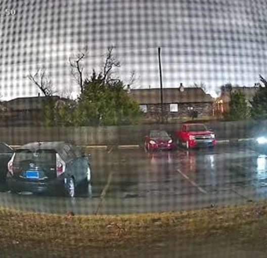 Parking lot with cars on a rainy night, viewed through a screen.