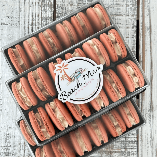 Two boxes of pink macarons with cookie halves and creamy filling.