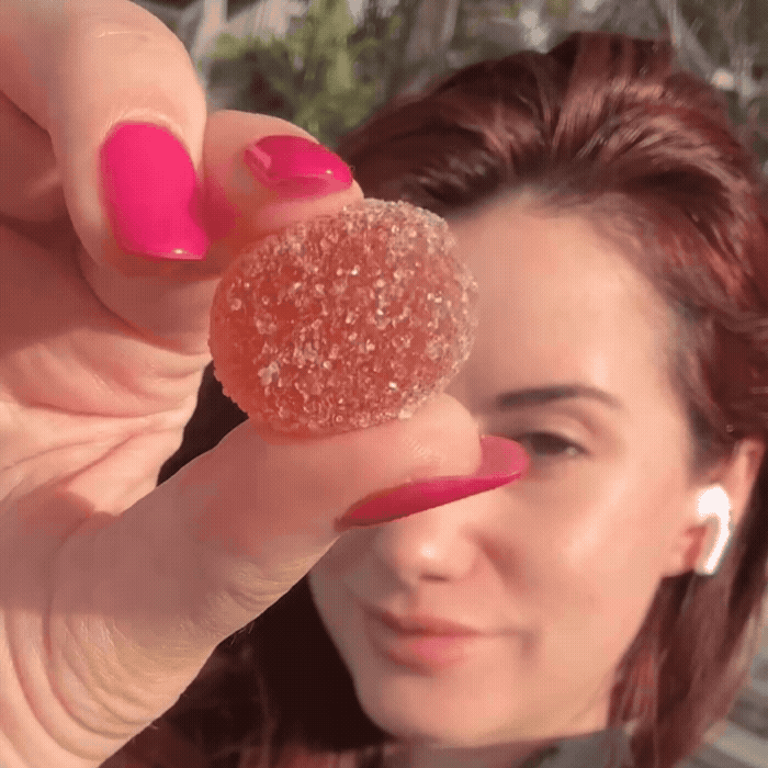 Person holding a sugar-coated gummy candy close to the camera.