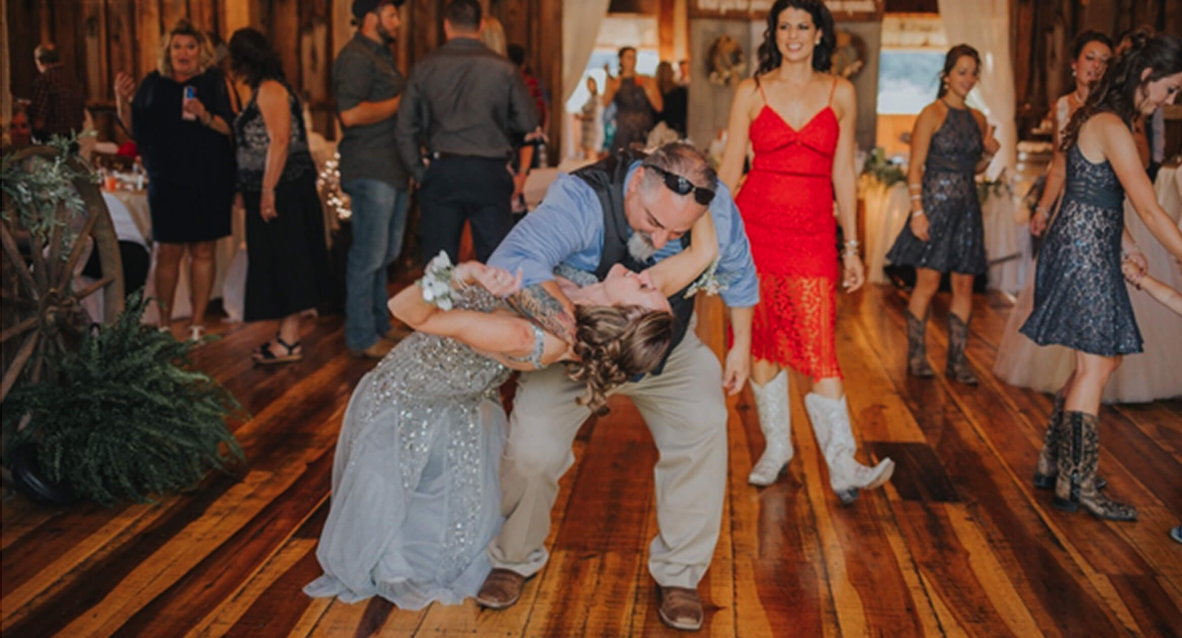 A bride and groom share a romantic dance at their wedding reception, surrounded by soft lighting and joyful guests.