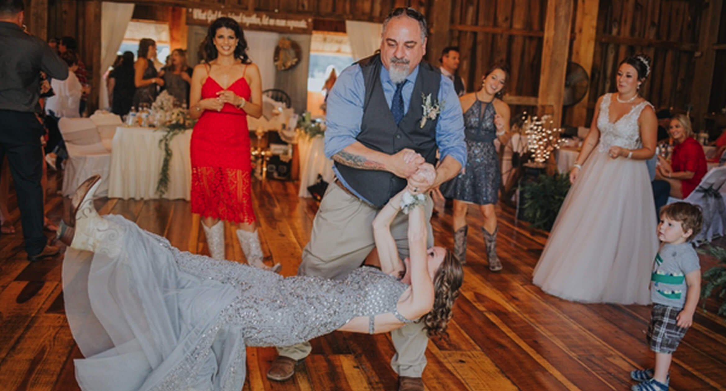 A man and woman joyfully dancing together on the wedding dance floor, surrounded by festive decorations and guests.