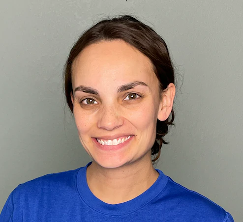 Person smiling in a blue shirt against a gray background.