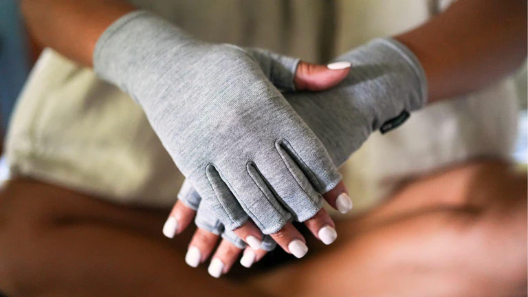 Hands wearing gray fingerless gloves, fingers interlocked.