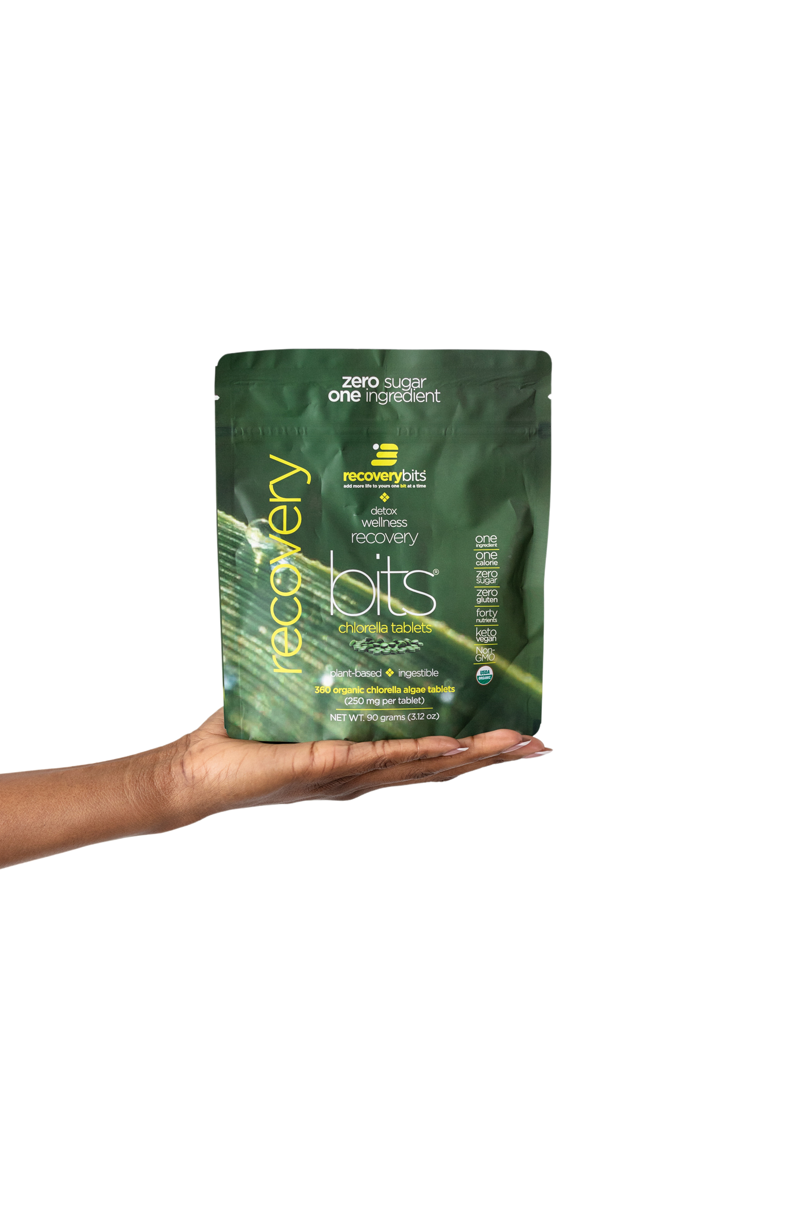 Hand holding a green package of chlorella tablets.