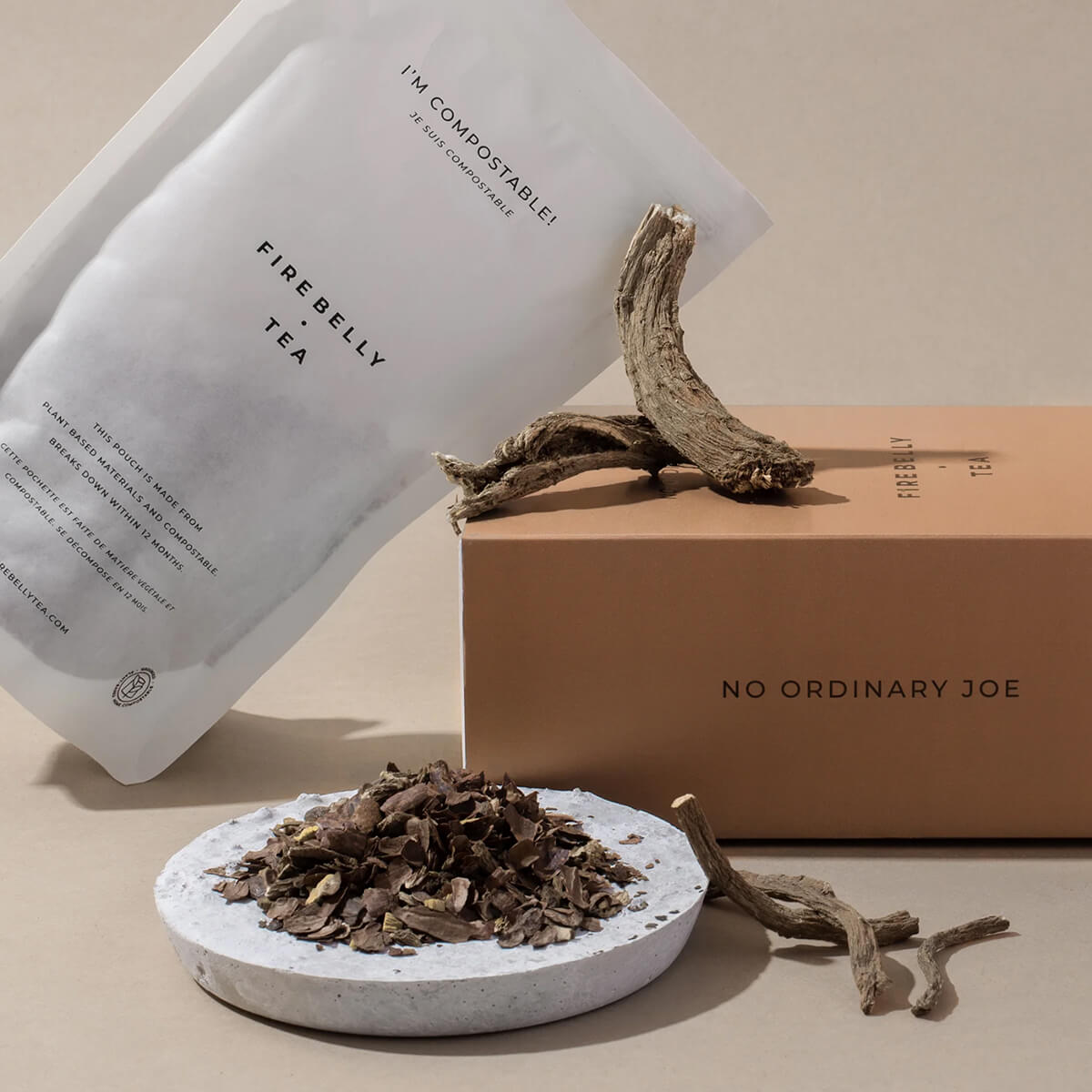 Compostable tea packaging with dried tea leaves and roots on a plate.
