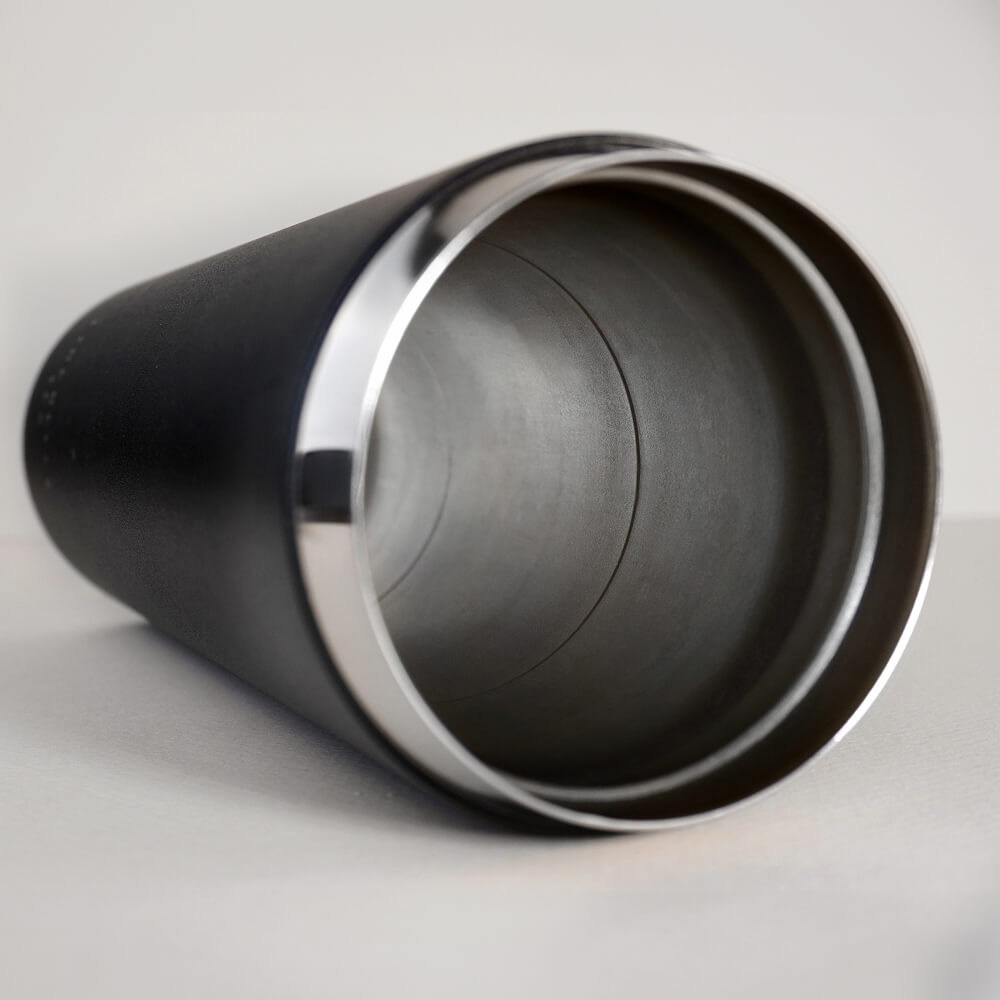 A close-up of a black insulated tumbler with a stainless steel interior, lying on its side.
