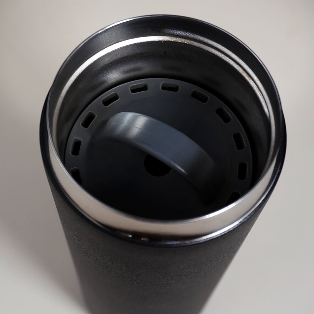 A close-up, high-angle shot of the inside of a black travel mug with a gray plastic insert.