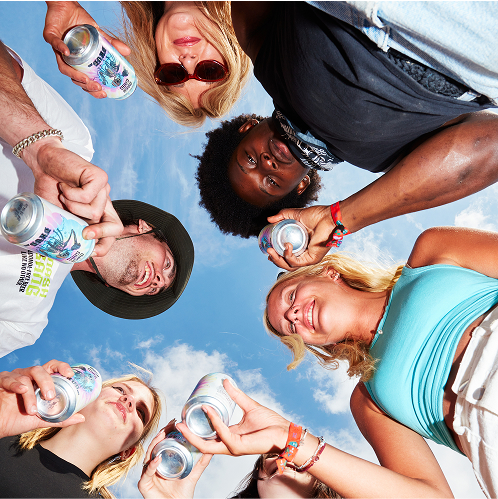 Group of people holding cans, looking down at the camera against a blue sky.