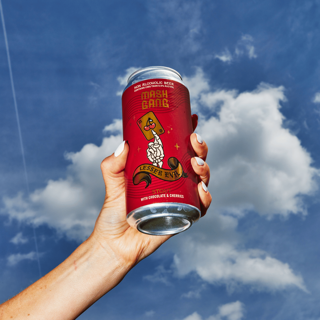 Hand holding a colorful can against a blue sky with clouds.