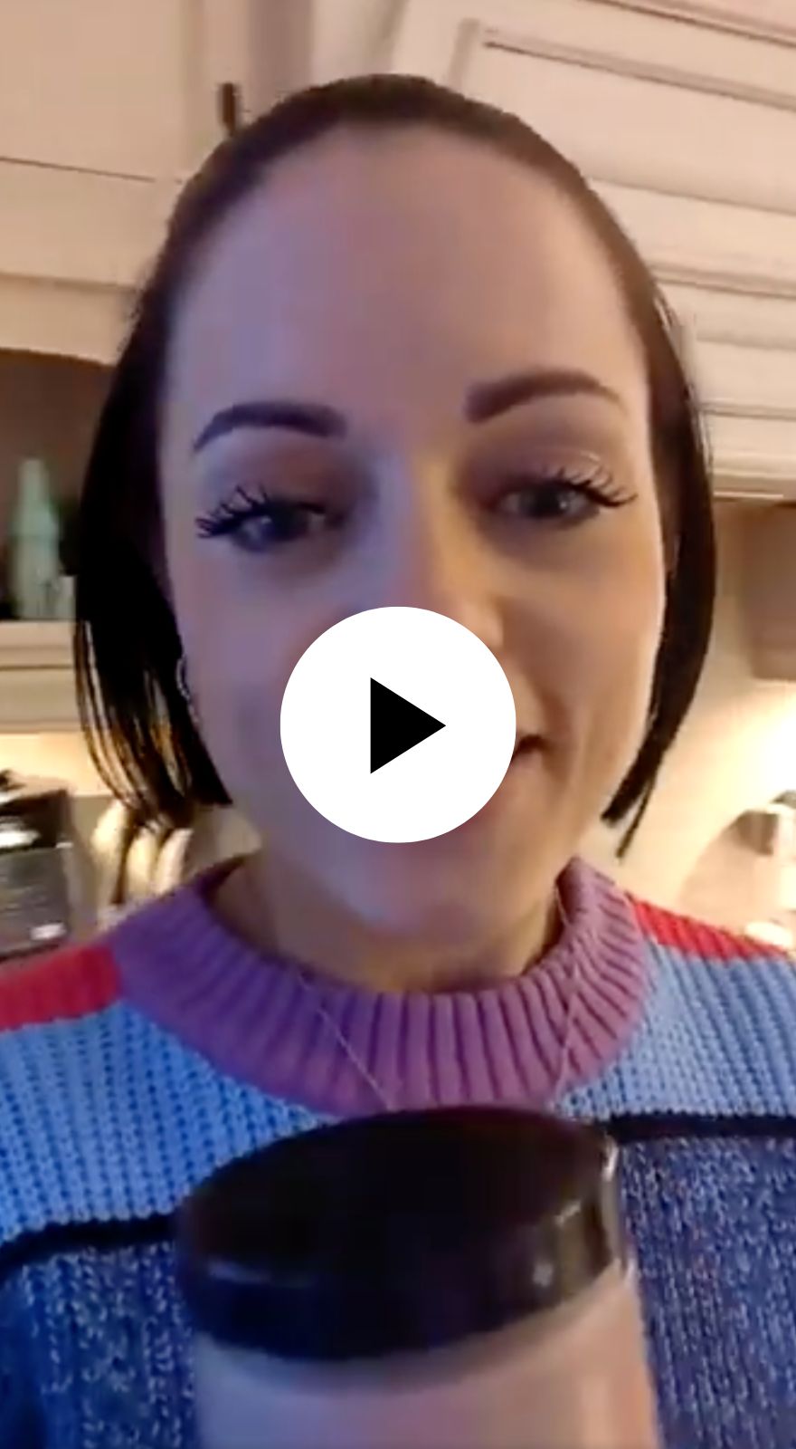 Person in a colorful sweater holding a container in a kitchen.