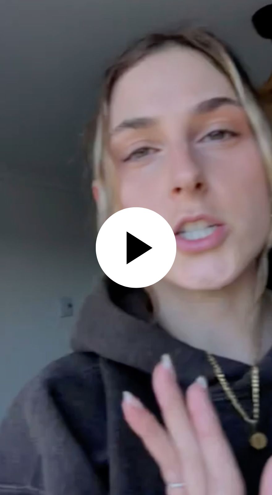Person speaking in a video with a play button overlay.