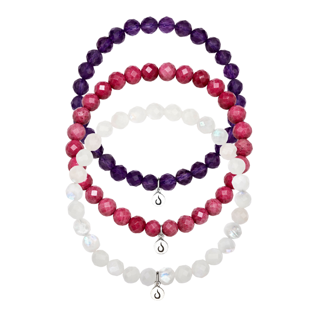 Three stacked bracelets with faceted beads in purple, pink, and white, each with a small silver charm.