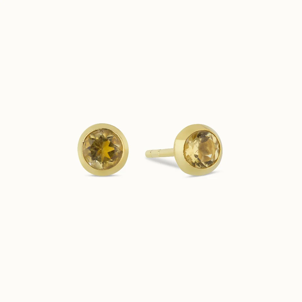 Two gold stud earrings with yellow gemstones.