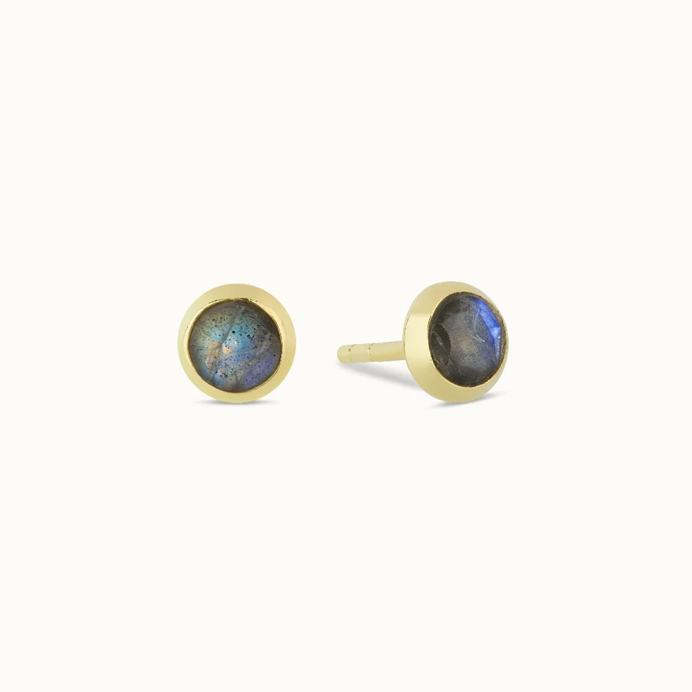 Two round stud earrings with blue stones set in gold.