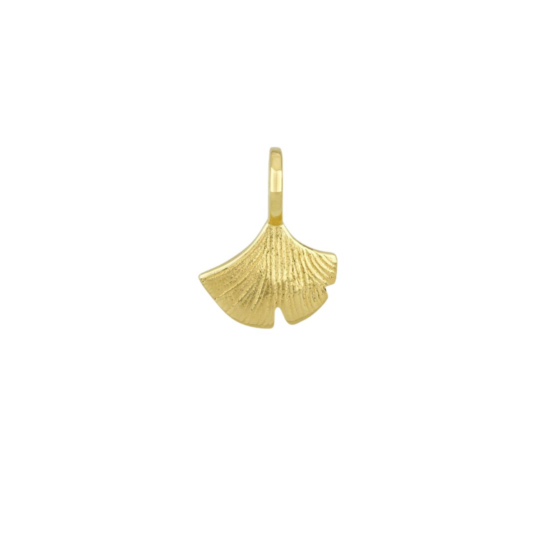 A close-up of a gold-colored pendant in the shape of a ginkgo leaf against a white background.