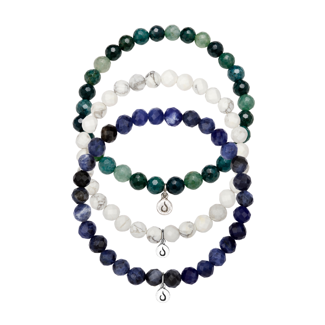 Three bracelets made of faceted green, white, and blue beads, each with a silver charm.