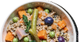 A close-up of a bowl of grains with peas, diced sweet potato, meat, and a pickled pepper.