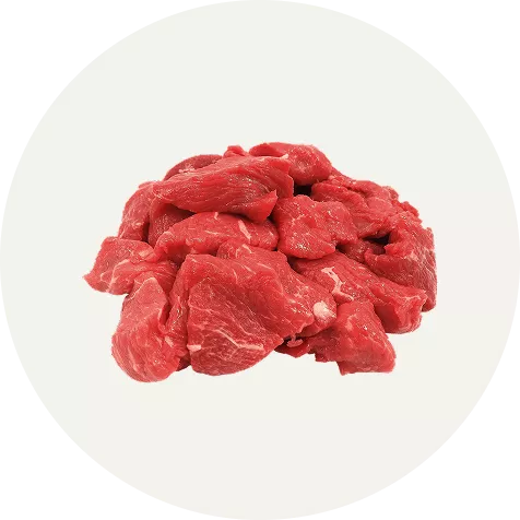 Pile of raw red meat chunks on a white background.