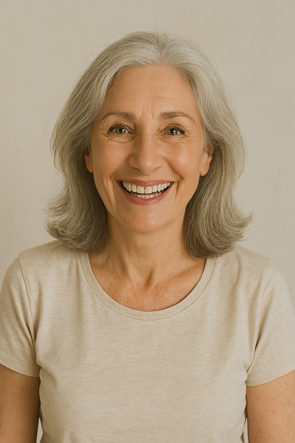 Smiling woman with gray hair wearing a beige shirt.