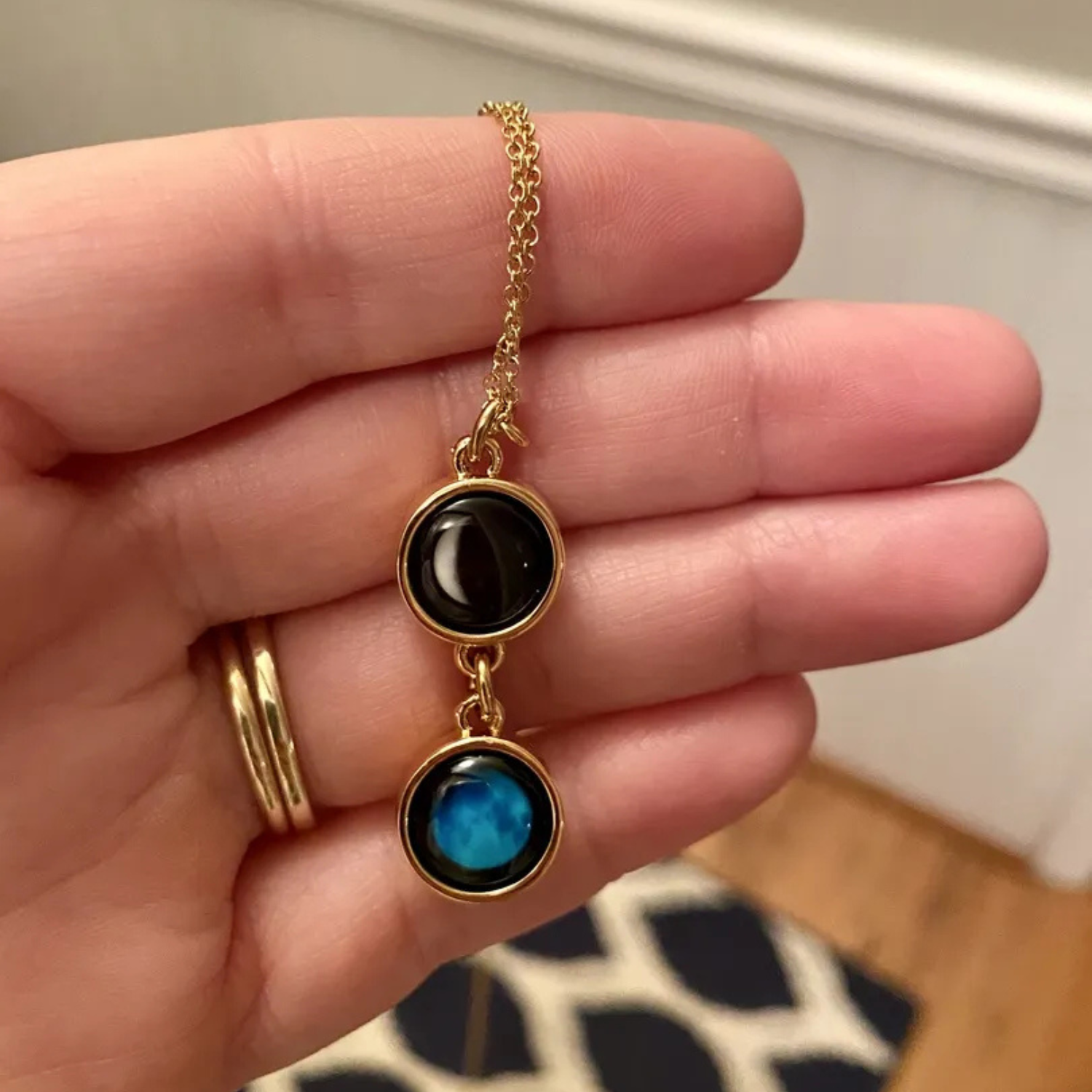 A hand holding a necklace with black and blue pendants.
