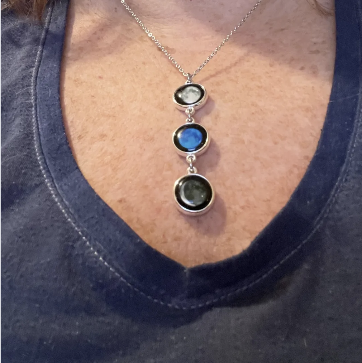 Triple stone pendant necklace on a blue shirt.