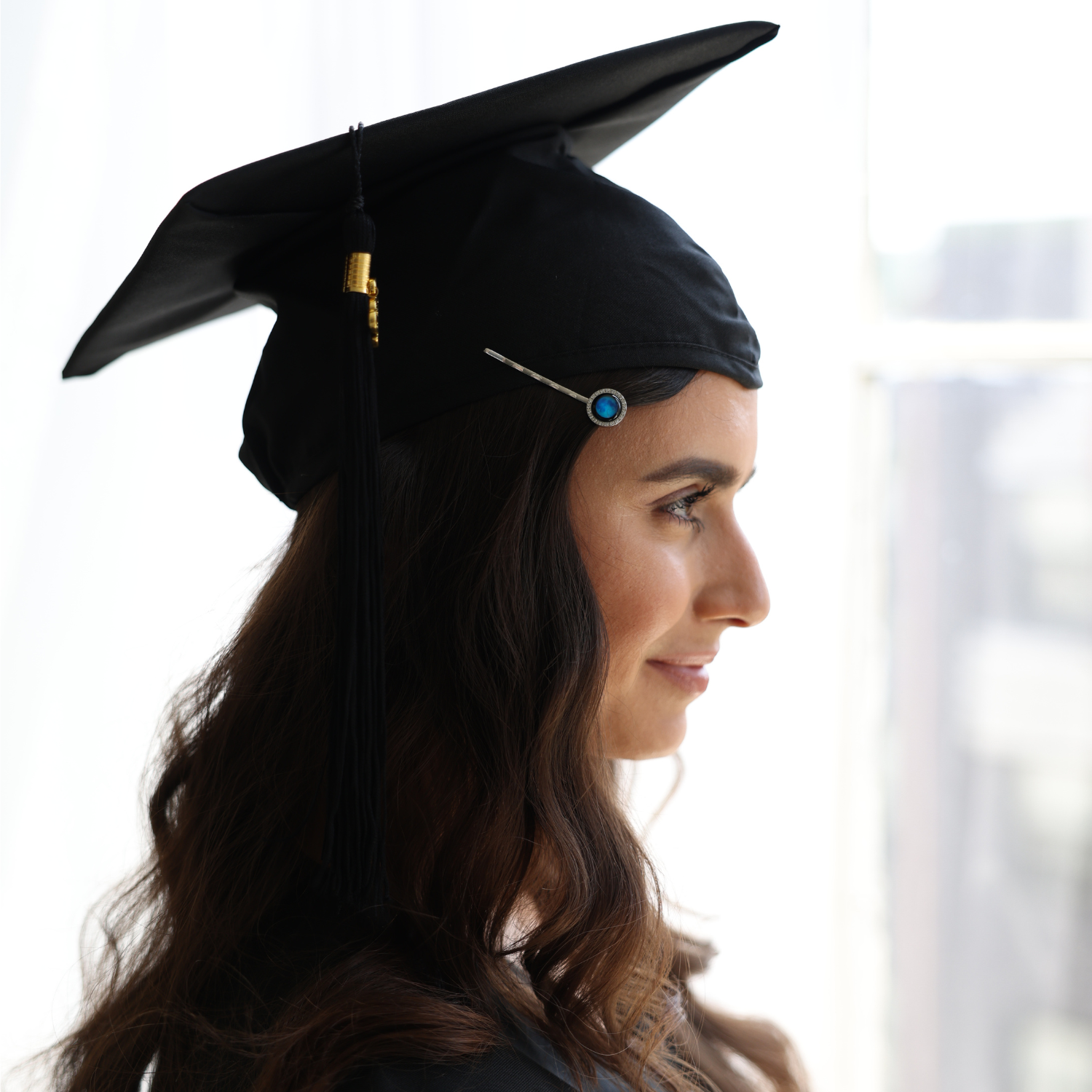 Profile of a person wearing a graduation cap indoors.