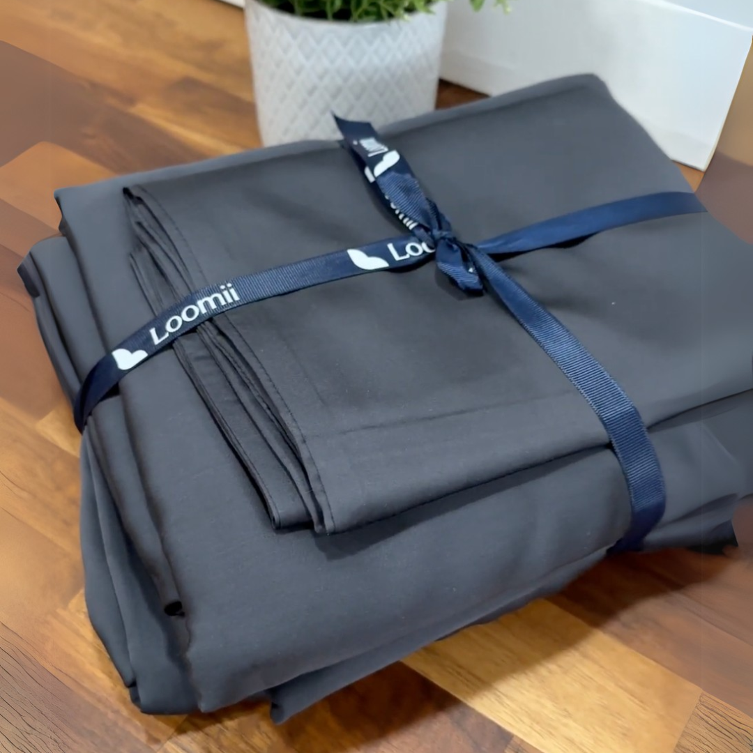 Folded dark sheets tied with a blue ribbon on a wooden surface.