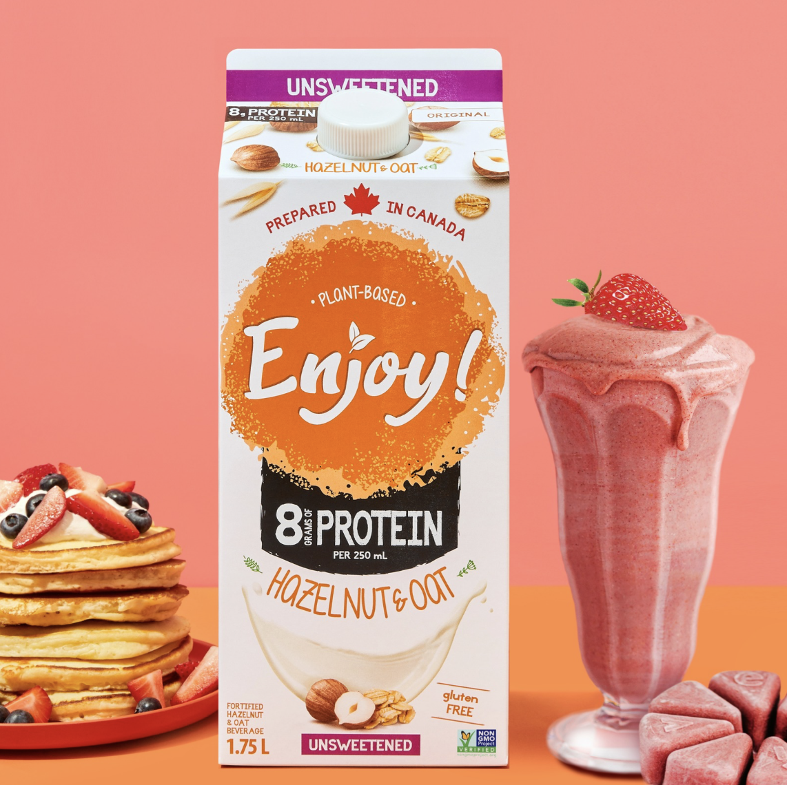 Carton of plant-based hazelnut oat beverage with pancakes and a strawberry smoothie.