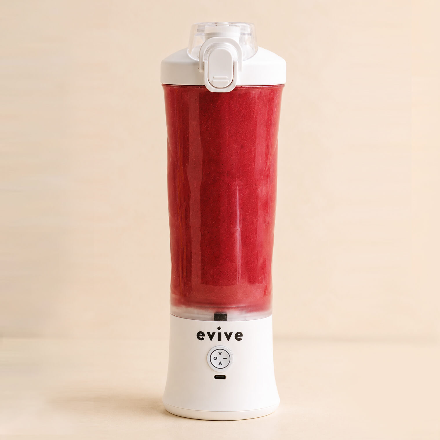 A white Evive portable blender filled with a red smoothie against a light-colored background.
