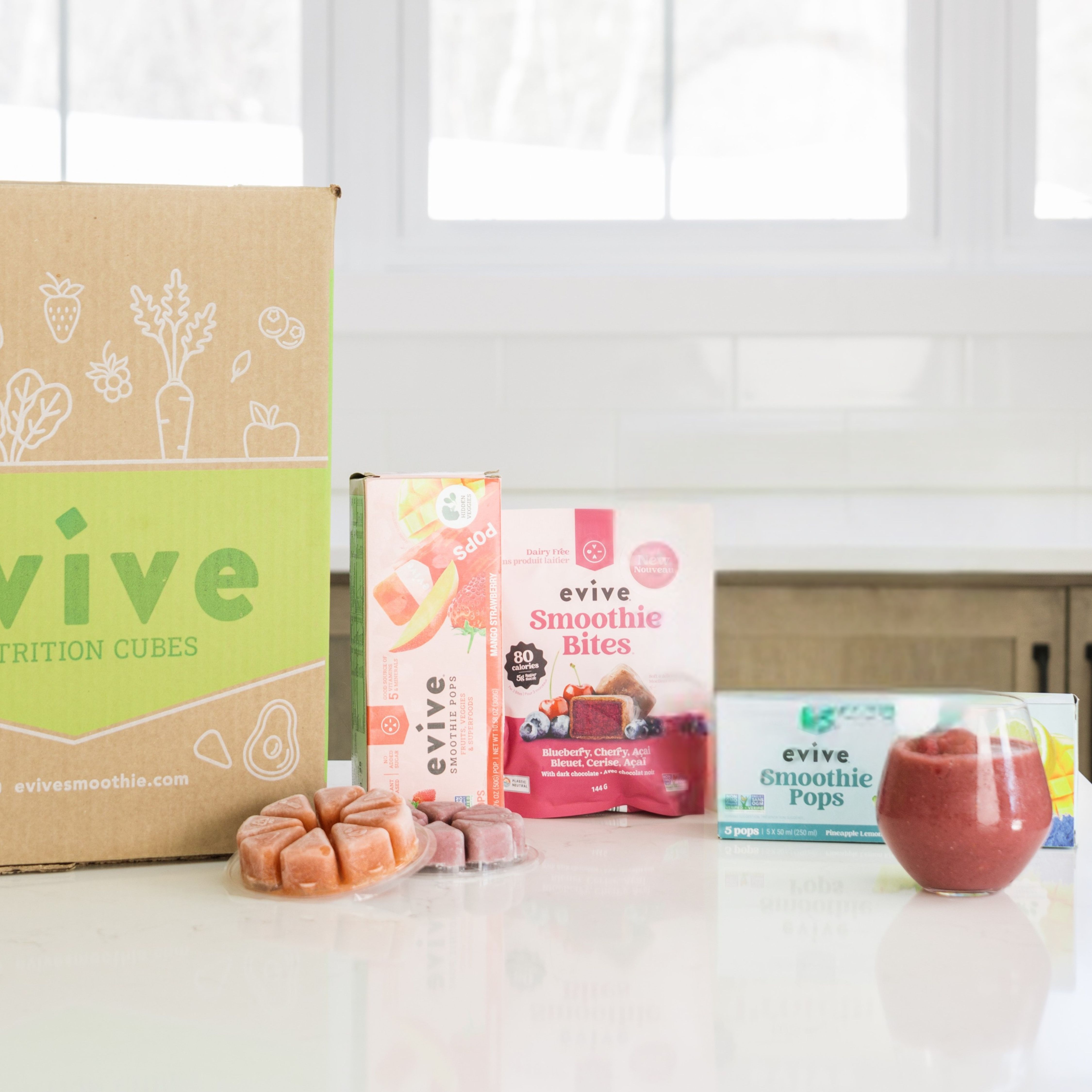 Assorted Evive smoothie products on a kitchen counter with a large box.