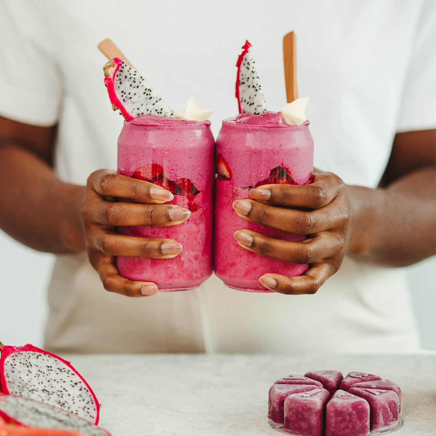 A person pours a blue smoothie into a bottle next to a bag of Evive plant-based protein.