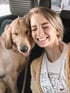Smiling person and a golden retriever sitting together in a car.