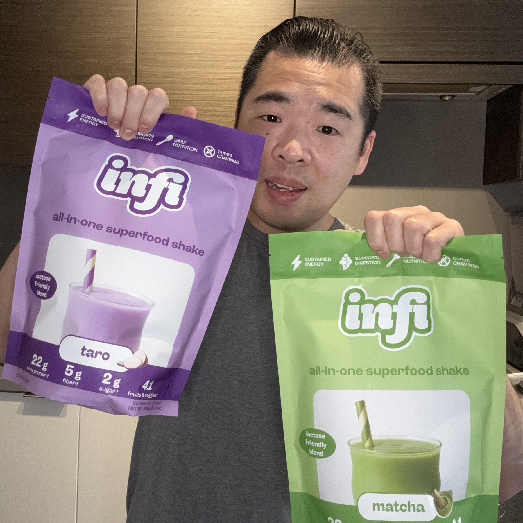 Person holding two bags of Infi superfood shake, taro and matcha flavors.