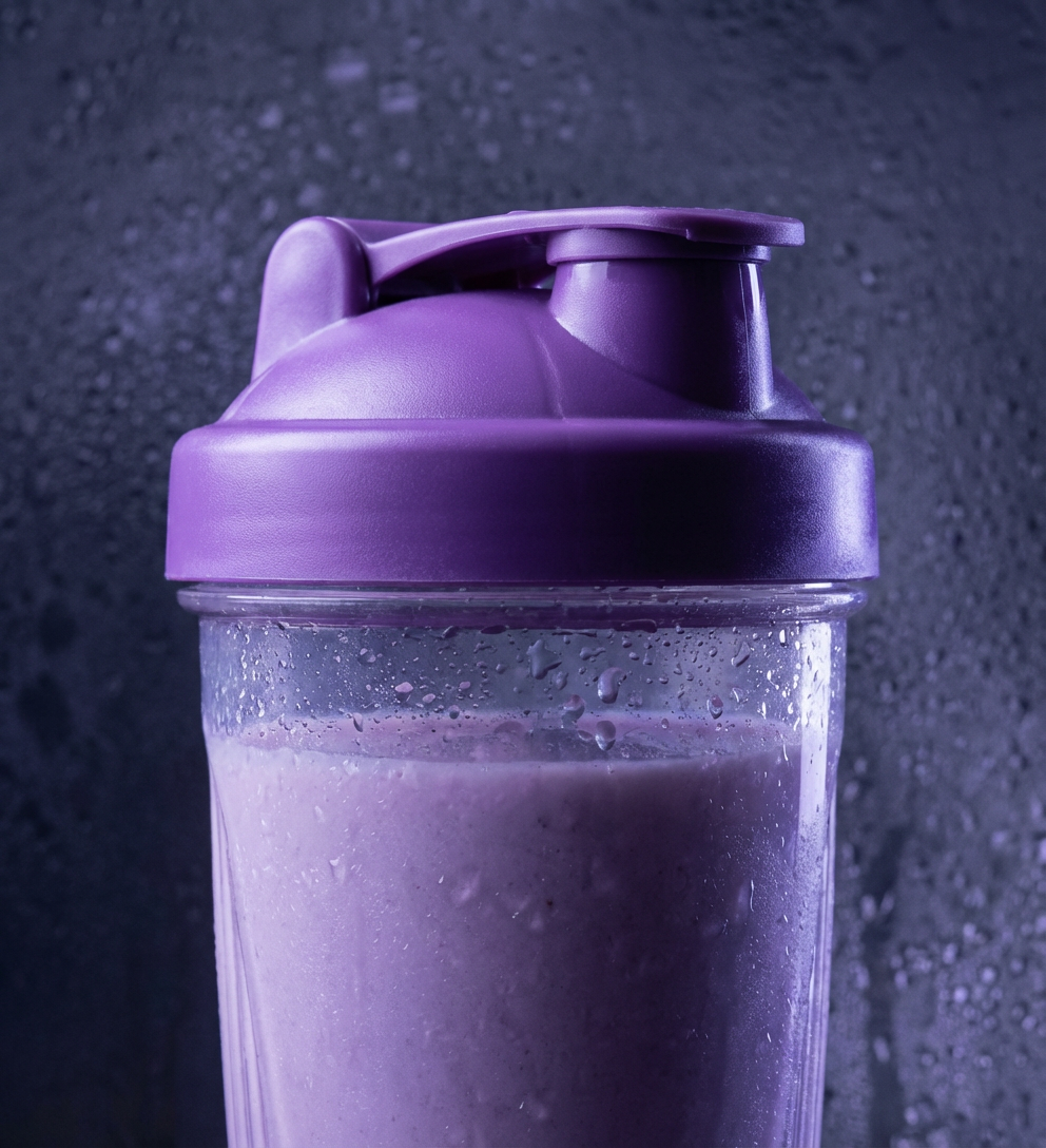 Close-up of a purple protein shaker bottle with condensation on its surface.