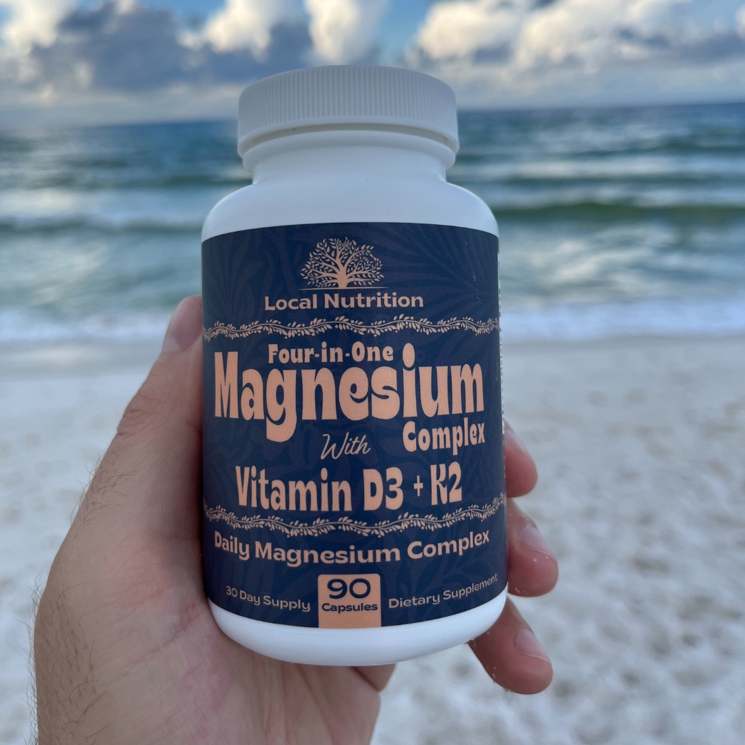 Hand holding a bottle of magnesium supplements at the beach.