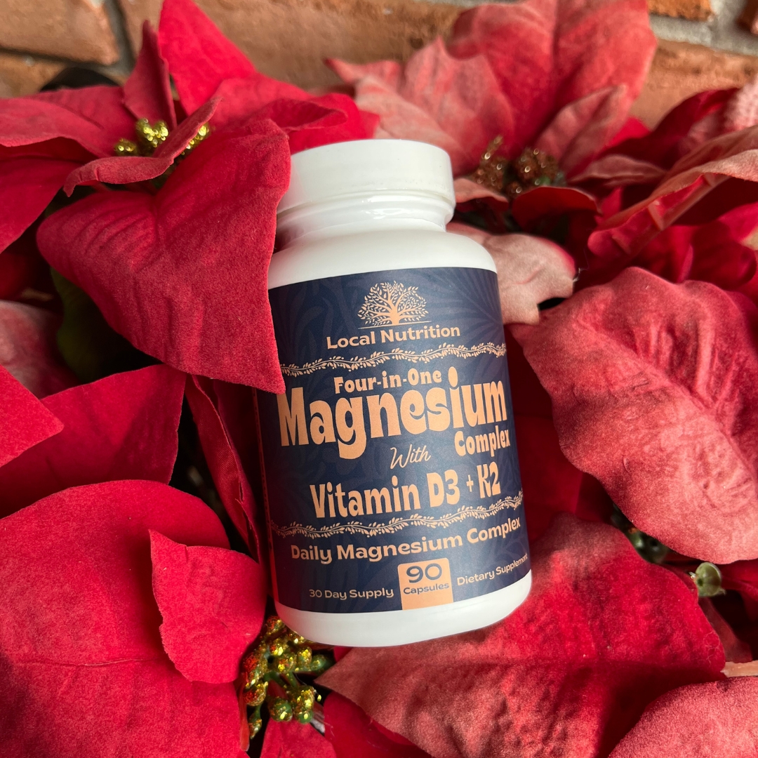 Container of magnesium supplement surrounded by red poinsettia flowers.