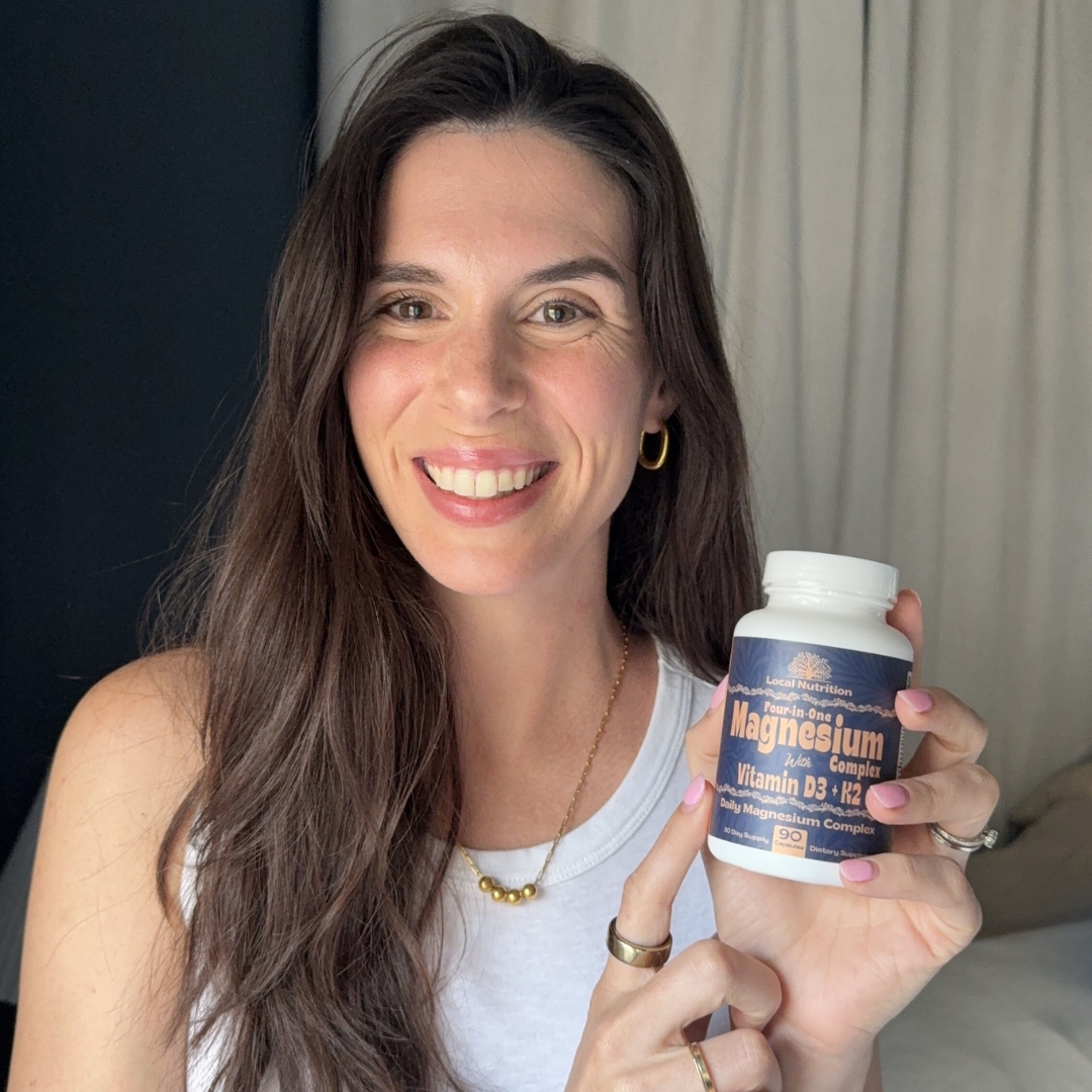 Person holding a bottle of magnesium vitamin supplement, smiling.