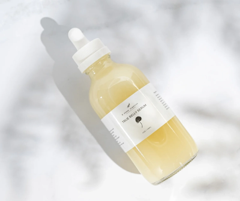 A glass bottle of 8 Sheep Organics True Belly Serum with a dropper on a white surface.