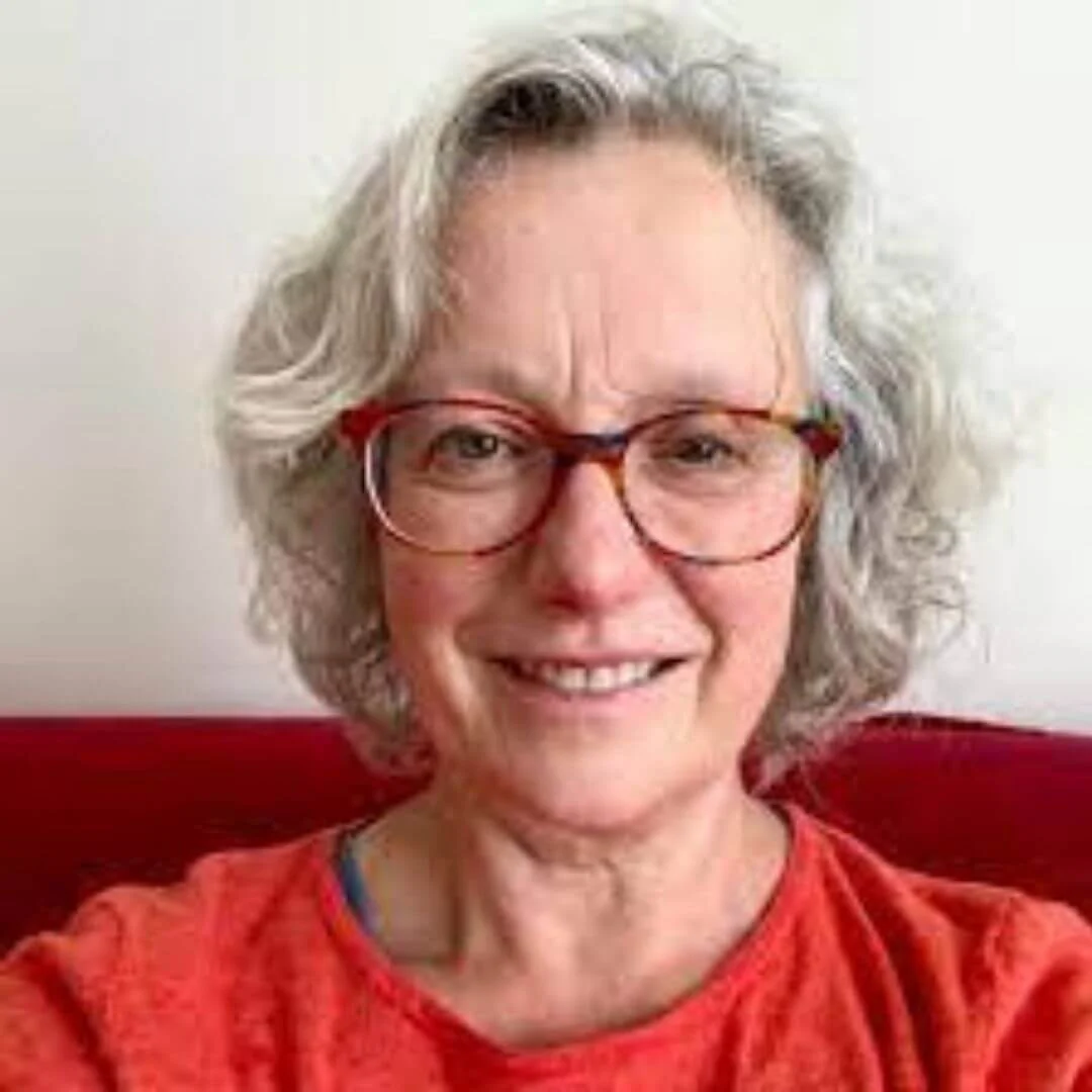 Person with gray hair and glasses smiling, wearing a red shirt.