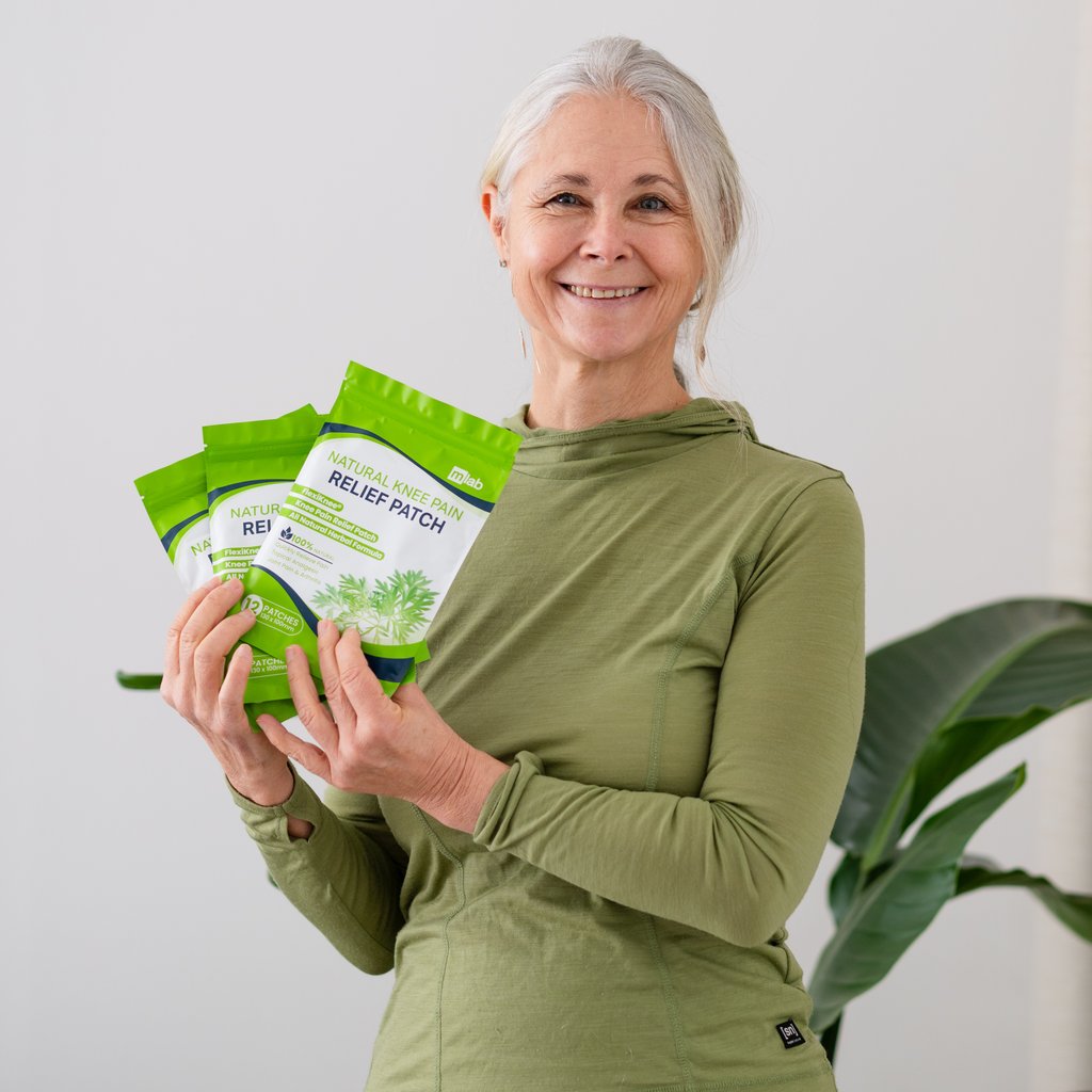 Person holding green knee pain relief patch packages, smiling.