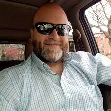 Man with sunglasses smiling inside a car.