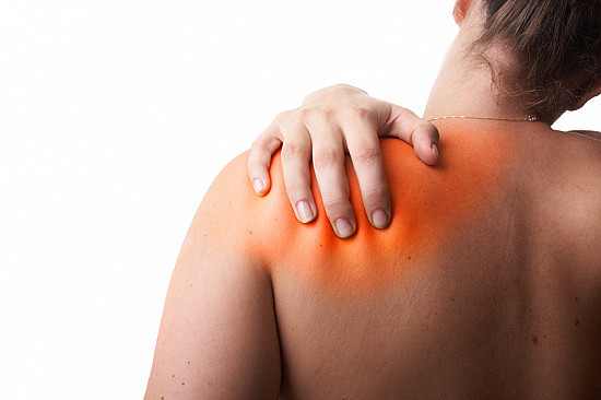 Person holding their shoulder with a red area indicating pain.