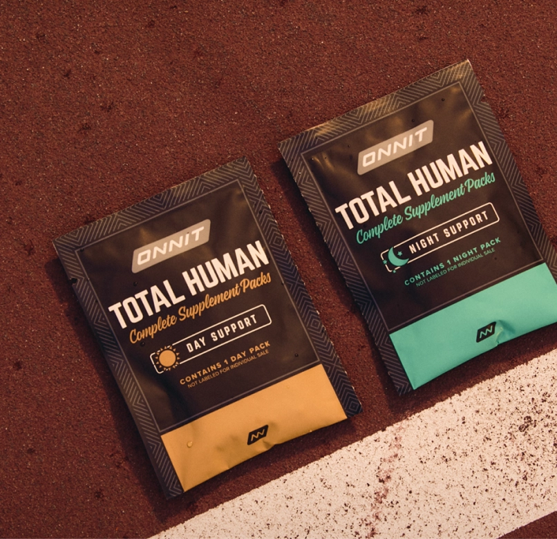 Onnit Total Human Day and Night supplement packs lying next to a white line on a textured surface.