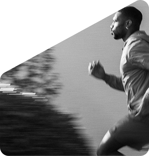 A man in a hooded jacket running in a black and white, motion-blurred photograph.